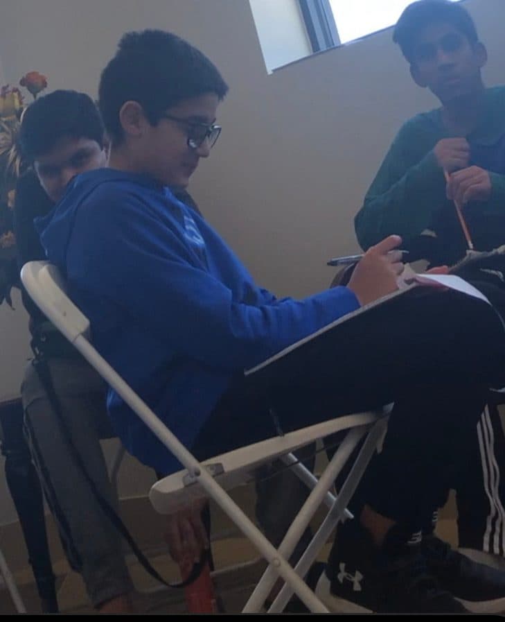 A teenage student writing intently in a notebook