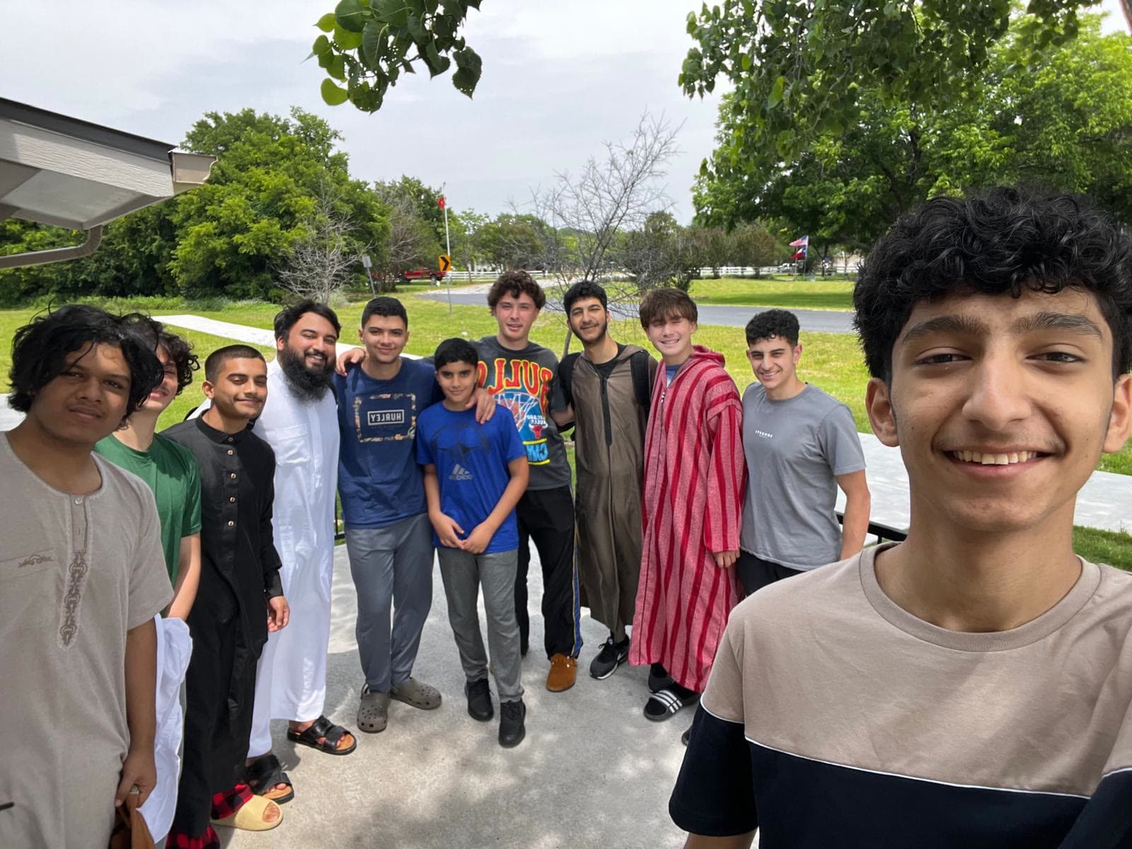 A group of students posing together outdoors on a campus green