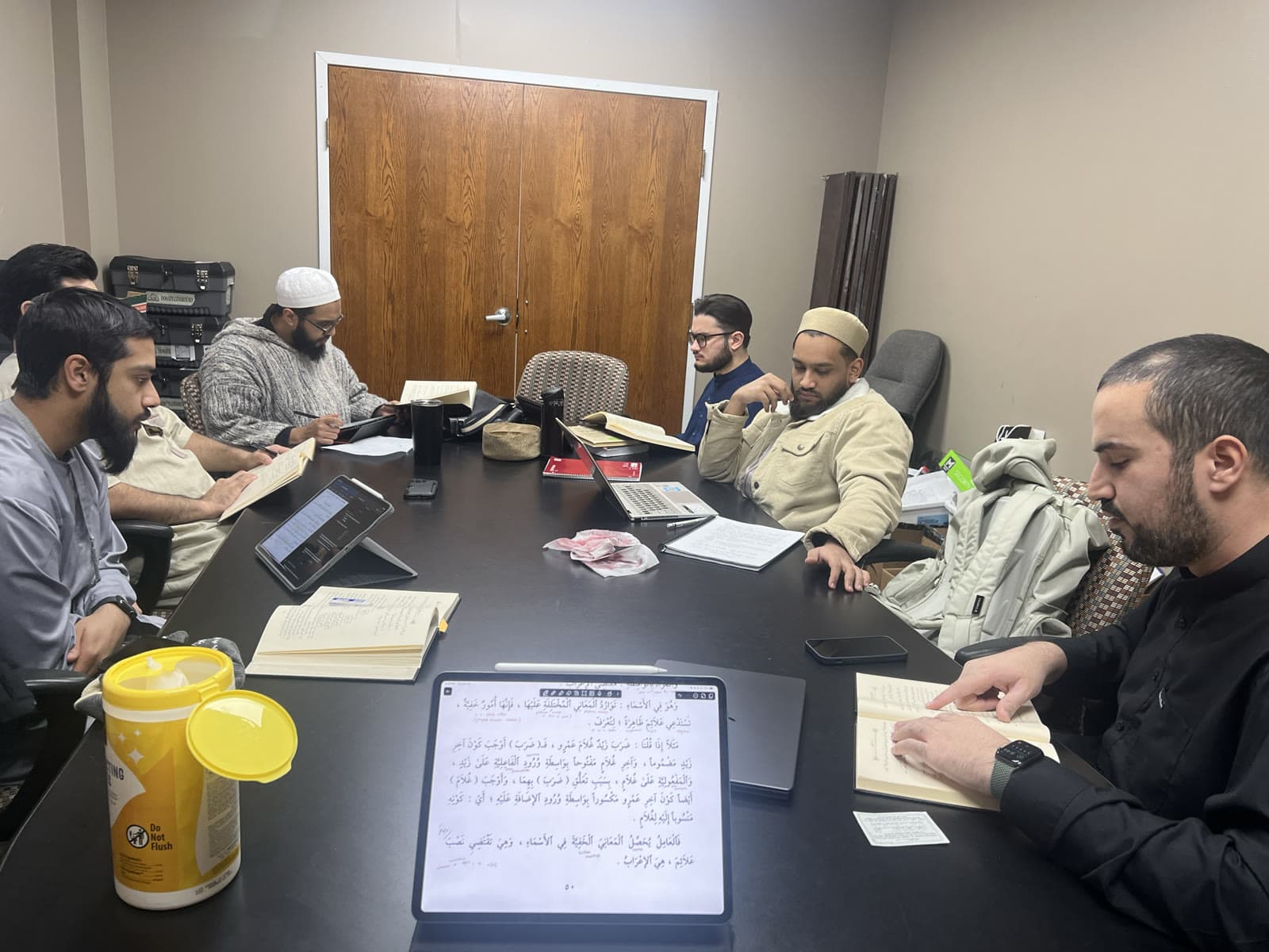 Students working through Arabic texts around a study table