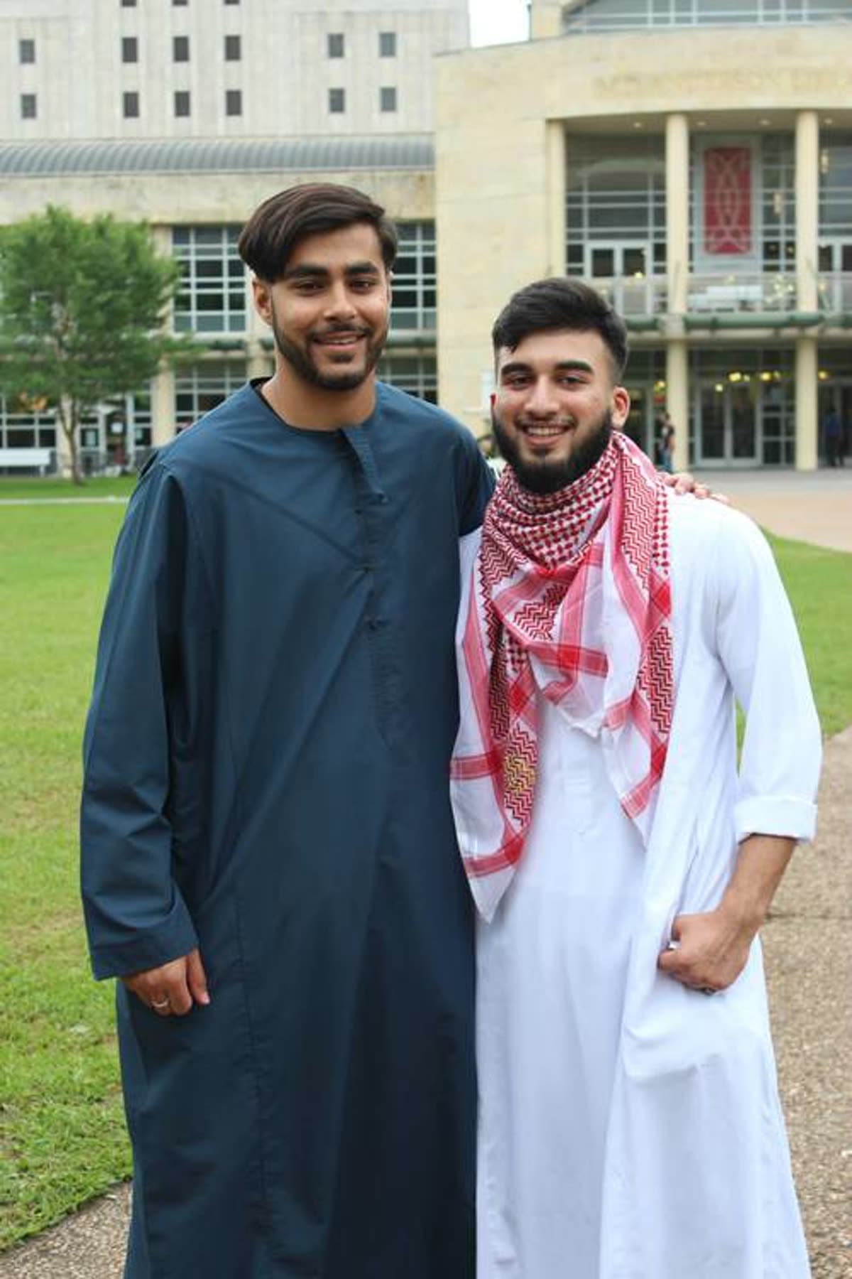 Two young men in thobes standing together on a university campus on Eid