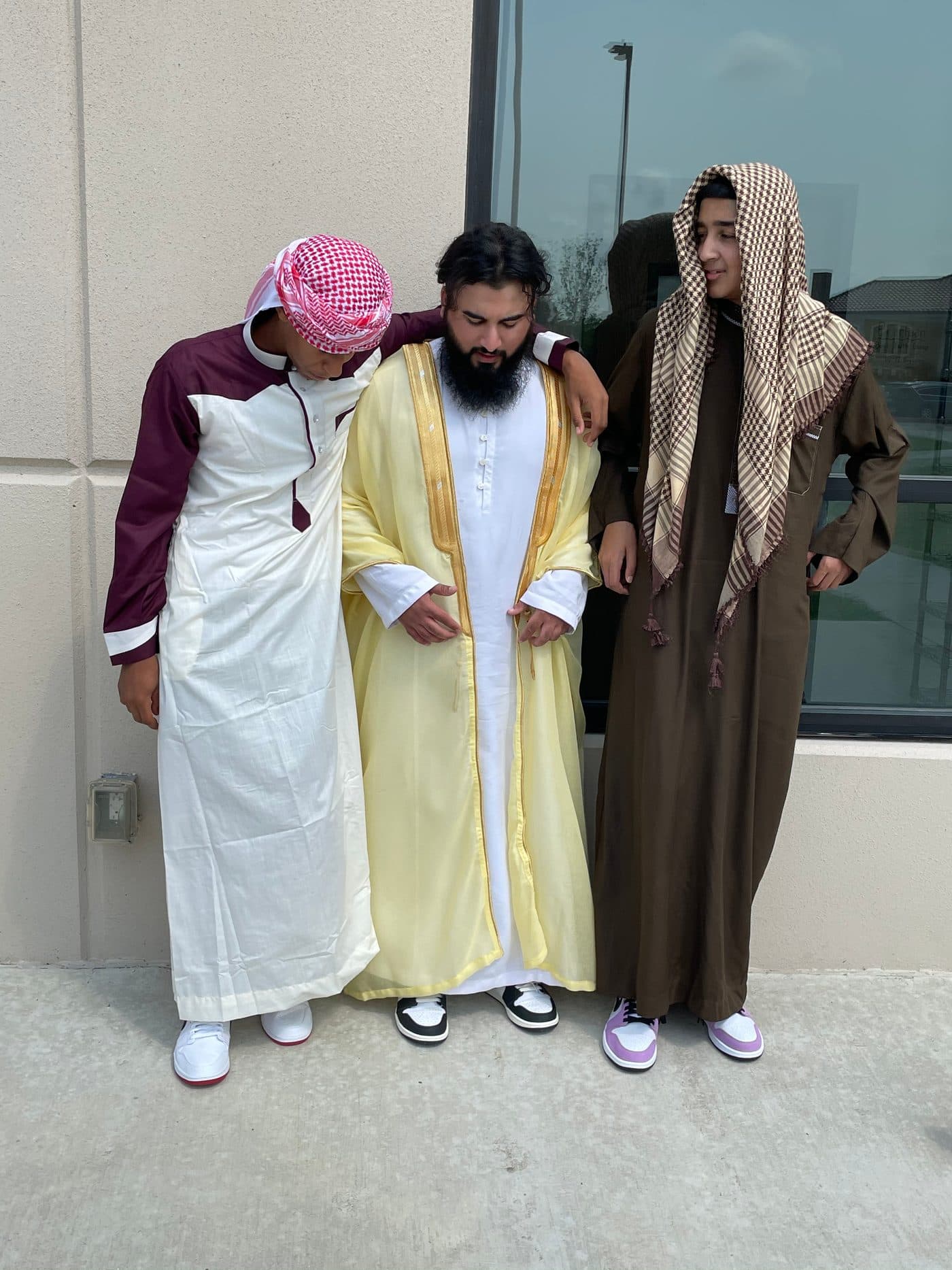 Three friends in traditional dress together after Eid prayer