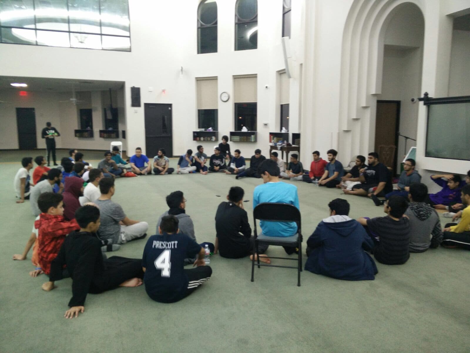 Students seated in a circle inside a masjid prayer hall