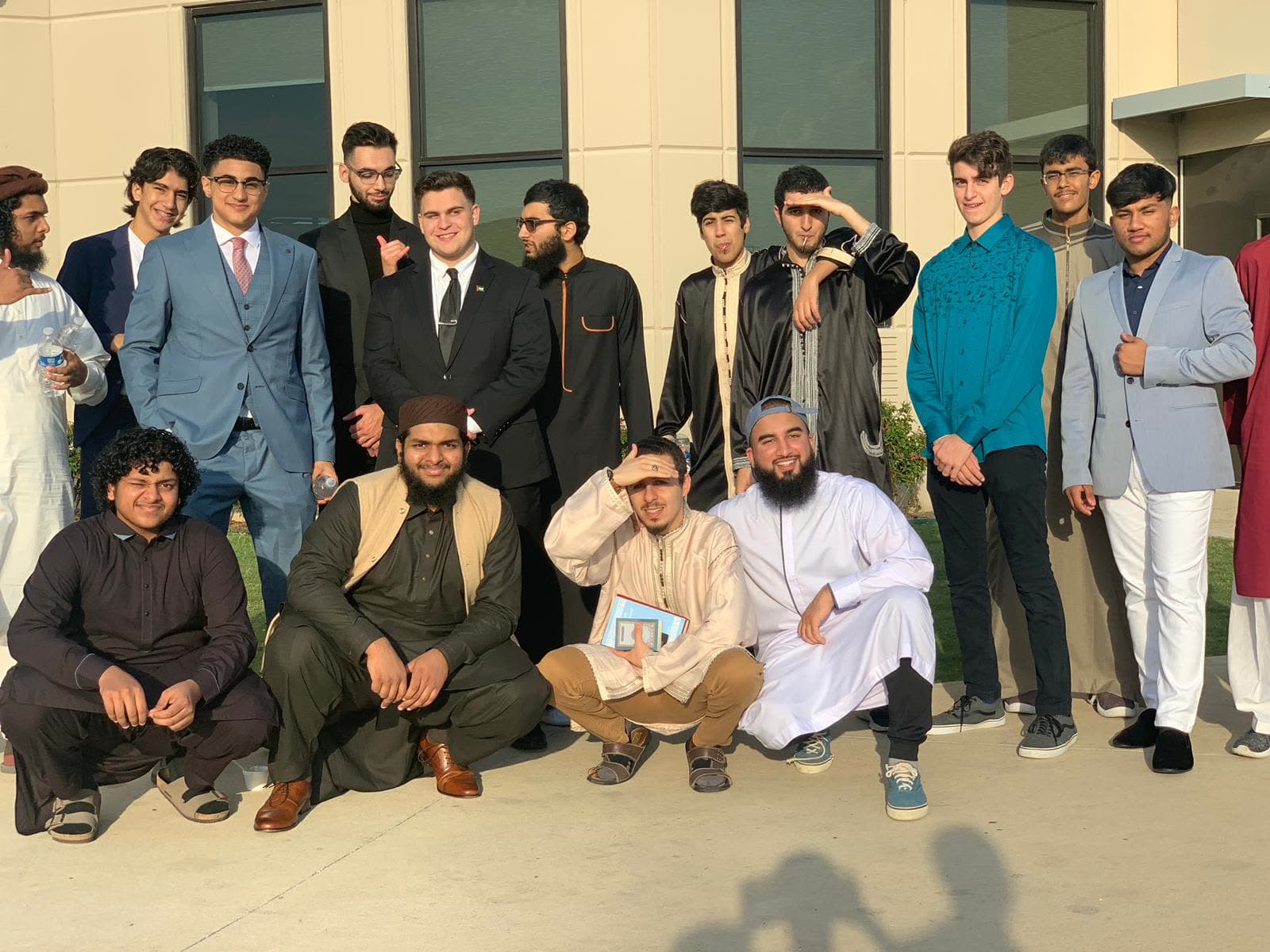A cohort of young men dressed for Eid gathered outside the masjid with their teachers