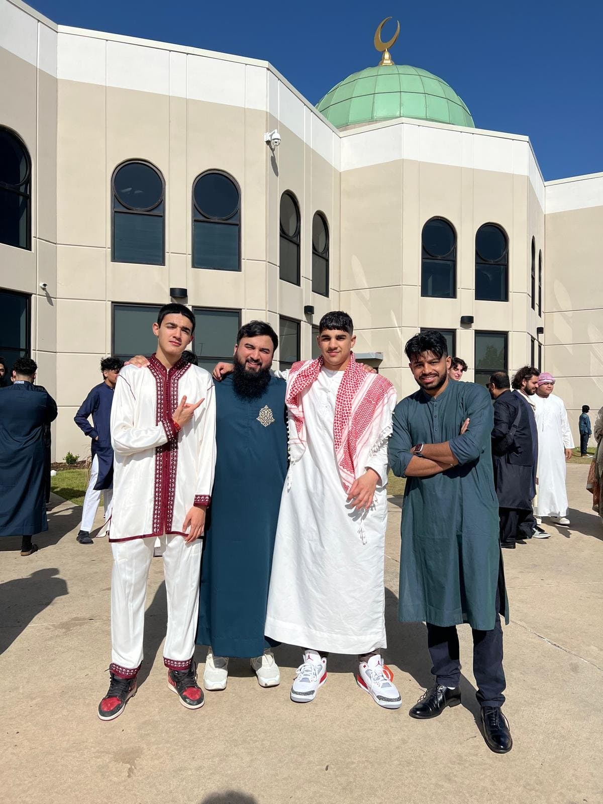 Students posing together outside a masjid in Eid clothing