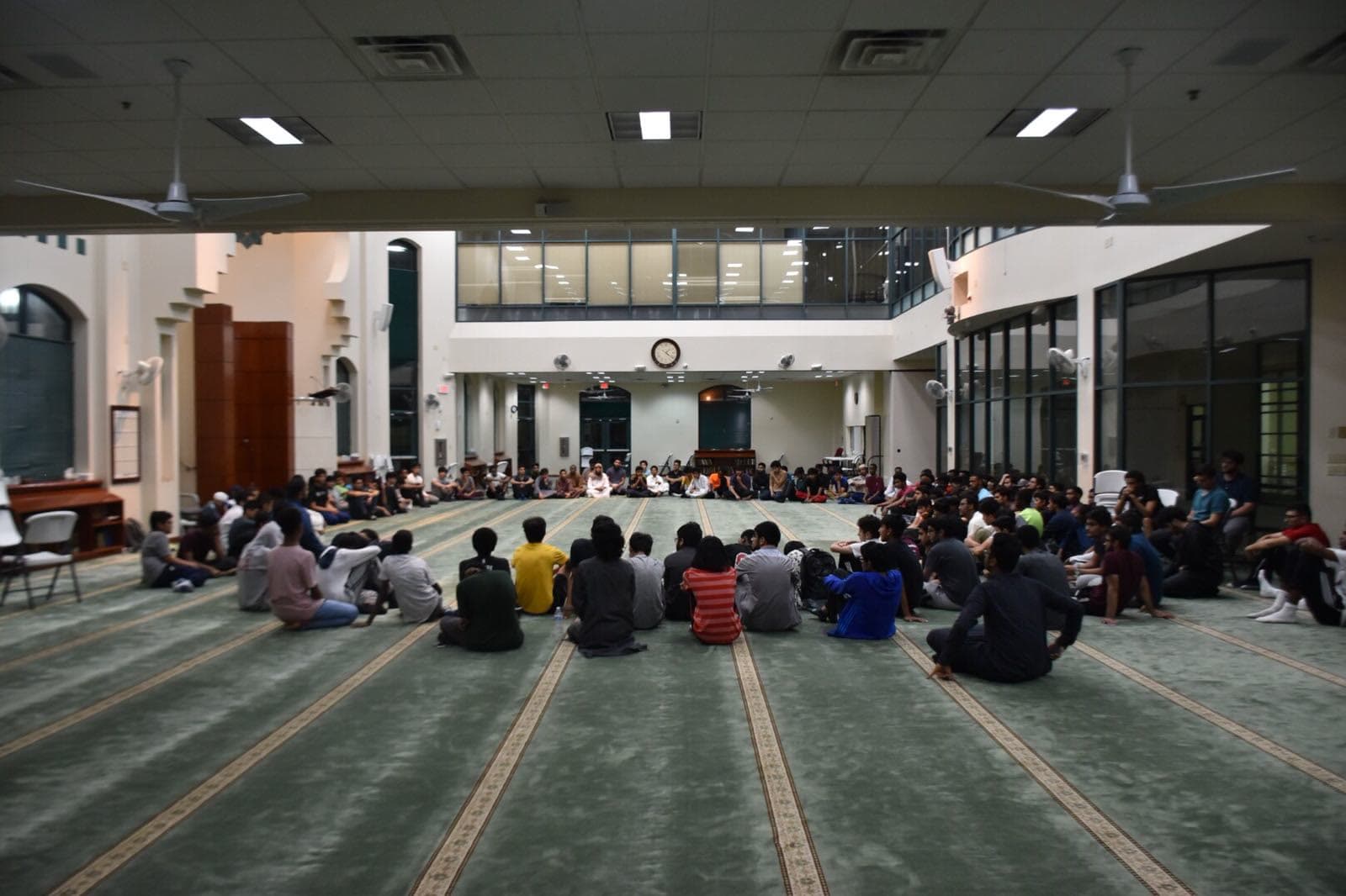 A large circle gathering in a masjid prayer hall