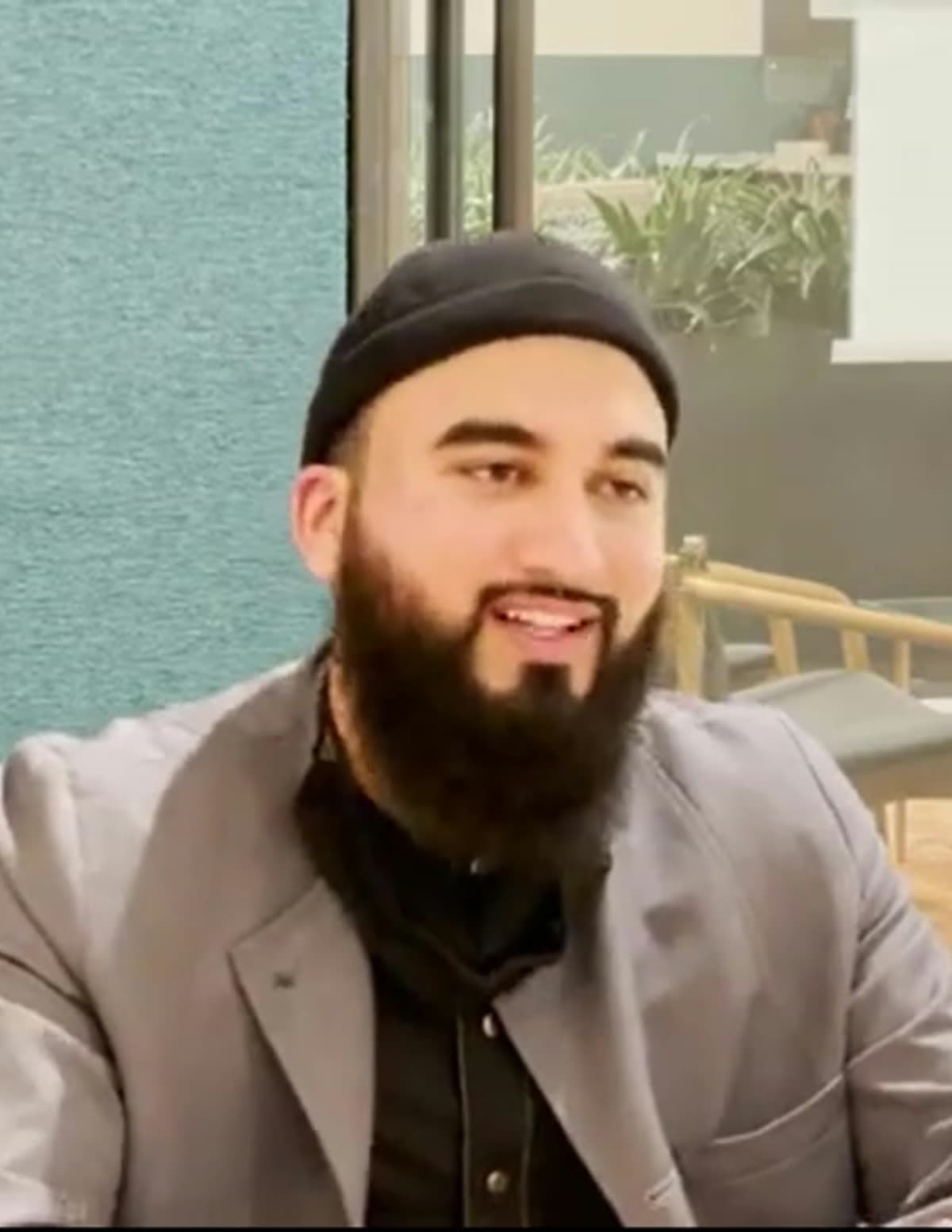 A young scholar in a cap and blazer, smiling mid-conversation