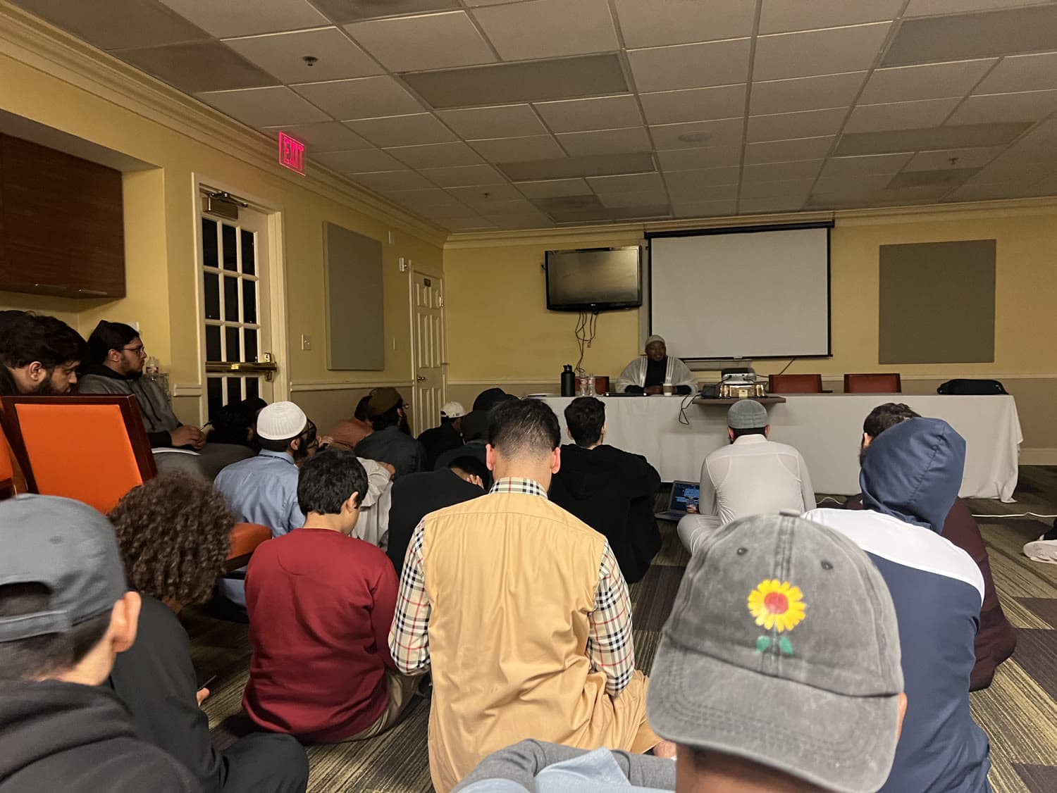 A hall of attendees seated for an evening program, seen from the back