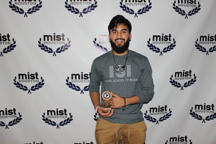 Irslan holding a trophy at a Qur'an recitation competition in an Islamic School of Irving shirt