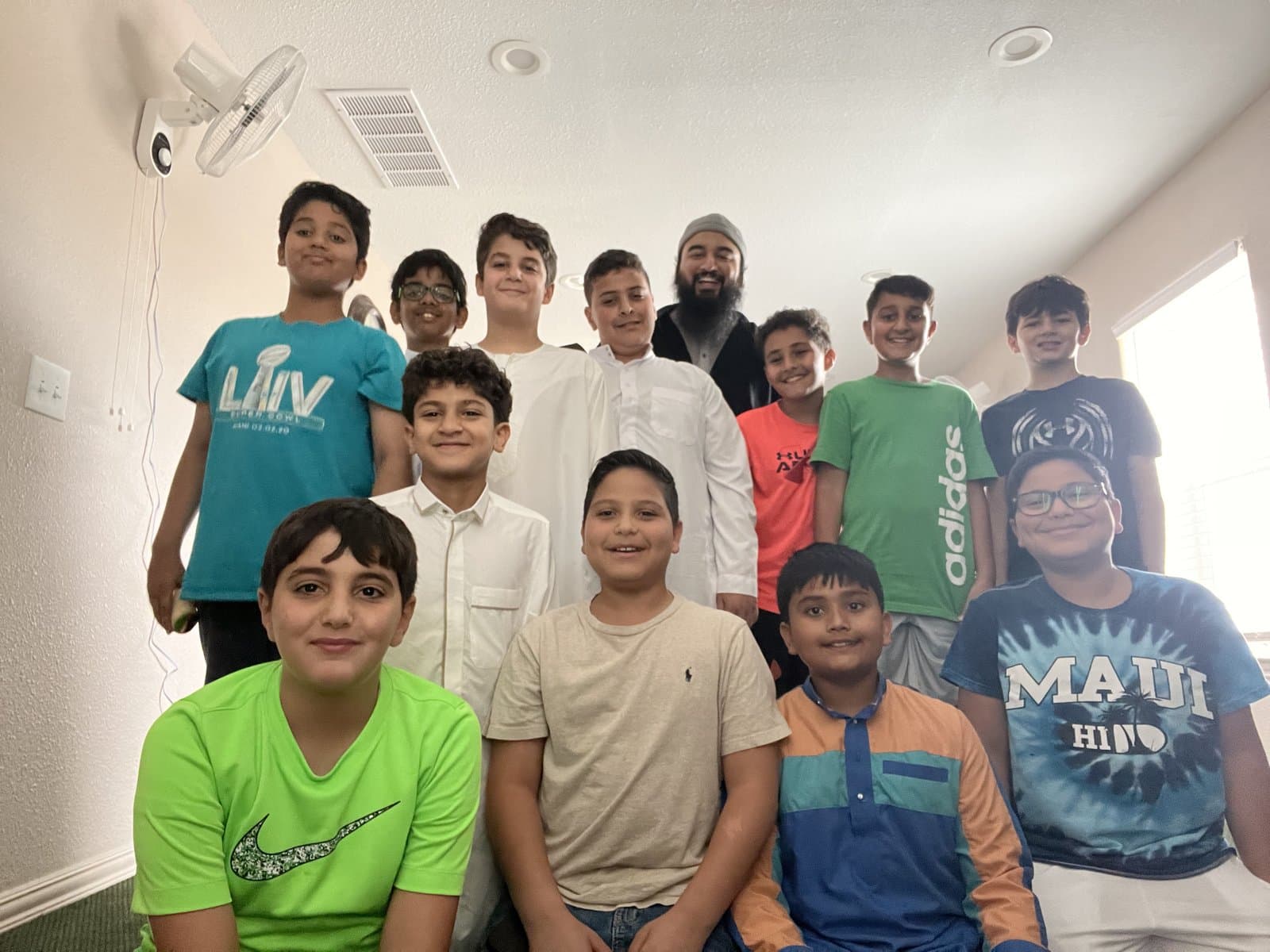 Irslan with a group of preteen students posing together indoors