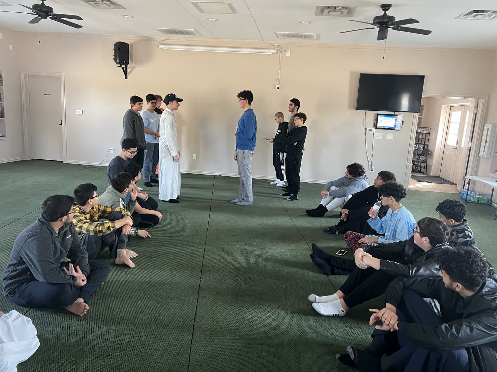 Irslan teaching a standing circle of teenage students in Sachse