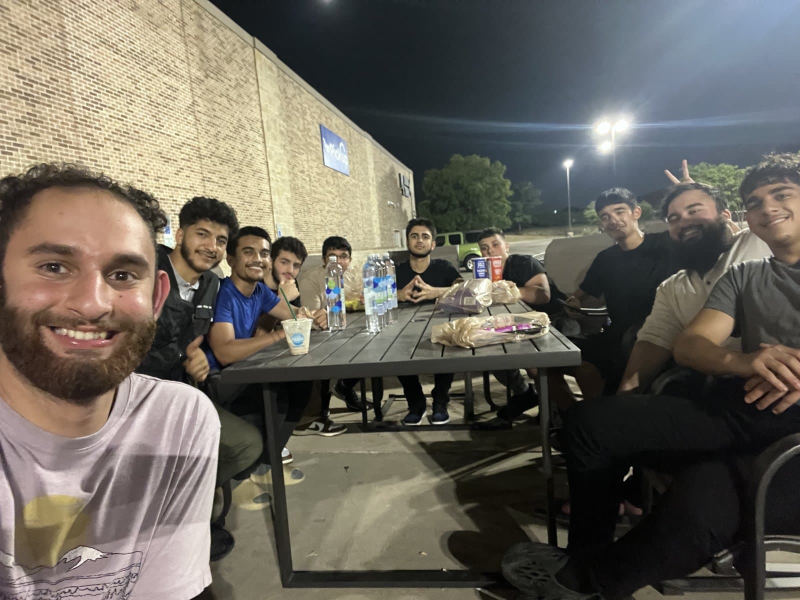 A large group of friends smiling together at a nighttime hangout