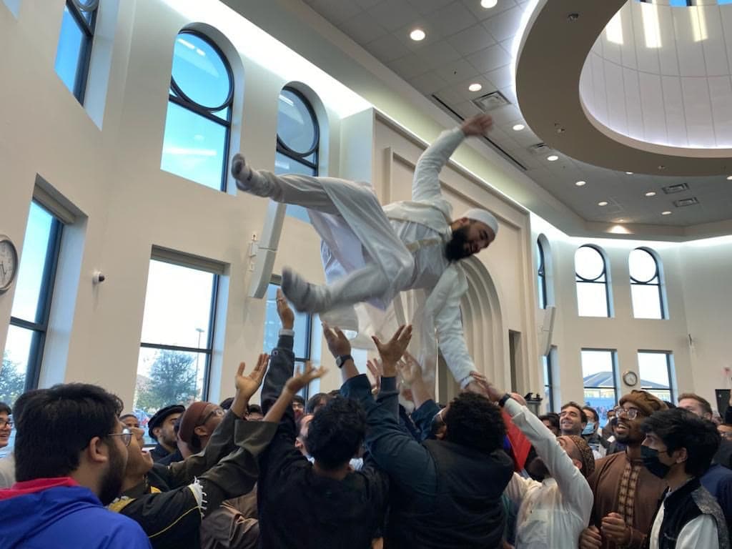 A student being tossed in the air by classmates in celebration